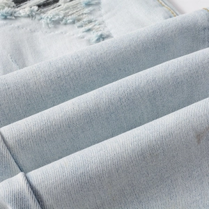 Gros plan détaillé du tissu denim bleu clair avec des déchirures et patchs usés