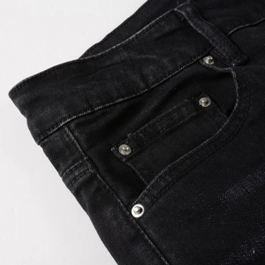 Close-up of black denim waist and front pocket featuring reinforced metal rivets