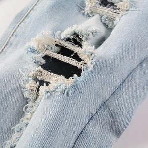 Vue macro d'un jean déchiré avec des franges blanches et une texture de denim vieillie