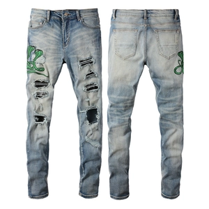 Jean slim bleu clair délavé avec broderie cobra verte et détails déchirés