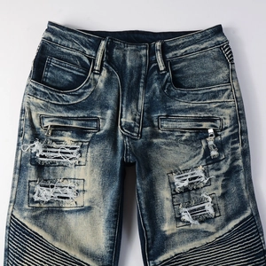 Detail of dark blue biker jeans featuring heavy wash, ripped effects, and ribbed knee panels