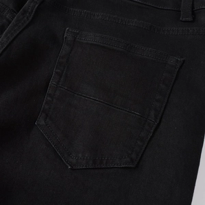 Detail of the back pocket on black distressed denim jeans with reinforced stitching