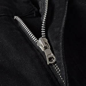 Macro shot of silver metal zipper closure on premium black slim-fit denim jeans