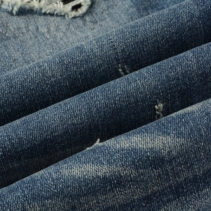 Vue macro de la texture denim bleu délavé avec détails de trous déchirés