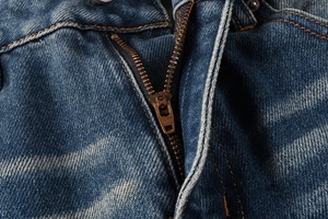 Detail of premium YKK metal zipper on vintage blue denim flared jeans for men