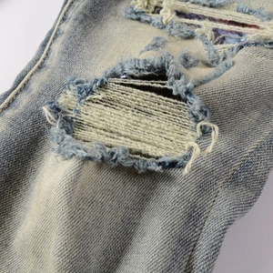 Détail d'un jean bleu clair avec détresse intense, bords effilochés et doublure tissée
