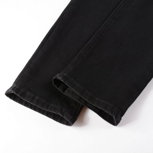 Detailed view of black denim pants leg opening featuring precise single-needle stitching