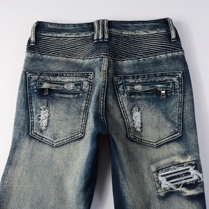 Detail of biker jeans showing pleated texture, metal zippers, and distressed denim fabric