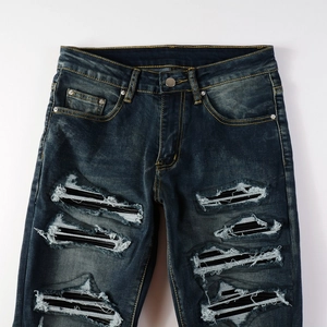 Detail of ripped blue denim jeans with black striped lining and contrast stitching