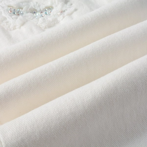 Detailed macro view of white denim fabric texture with colorful rhinestone and lace embroidery