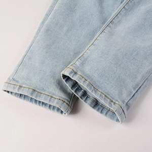 Détail du bas de jambe de jean bleu clair montrant l'ourlet à double couture précis