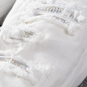 Men's slim straight white jeans featuring distressed patches with colorful rhinestones