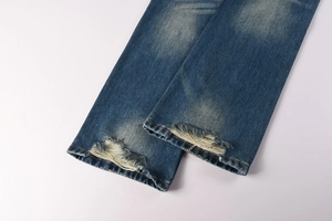 Detail of distressed hem on dark blue flare jeans with vintage washed denim effect