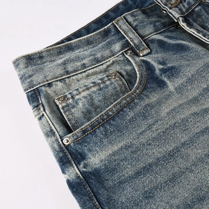 Détail du jean bleu clair délavé avec rivets métalliques et passants de ceinture renforcés