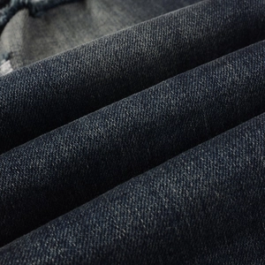 Macro shot of dark blue denim fabric showing twill weave and washed texture details