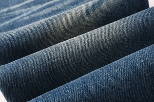 Detailed close-up of indigo blue denim fabric with natural washed texture and twill pattern