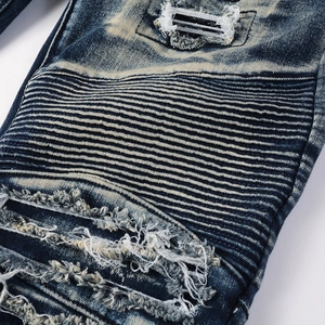 Close-up of distressed denim knees with biker style ribbed panels and frayed hole details