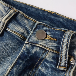 Détail de la taille en denim bleu foncé vieilli avec bouton argenté et coutures jaunes