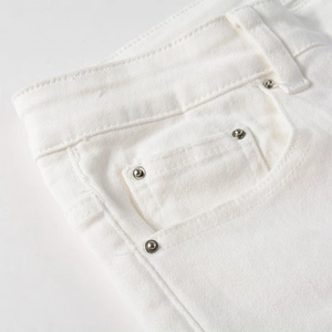 Close-up of premium white denim jeans featuring silver metal rivets and waist stitching