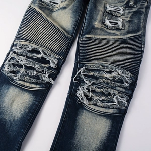Close-up of distressed denim jeans with biker pleats, ripped holes and vintage wash effect