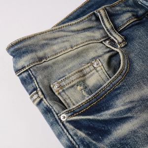 Vue détaillée de la taille d'un jean vintage avec rivets et texture délavée bleu foncé