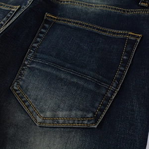 Close-up of vintage washed blue denim pocket with golden yellow contrast stitching details
