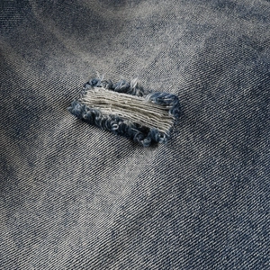 Gros plan sur le tissu denim bleu délavé avec détails de déchirures horizontales