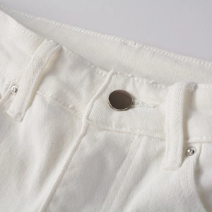 Dettaglio ravvicinato della vita in denim bianco con bottone metallico e rivetti vintage