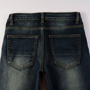 Detail of deep blue washed denim jeans featuring vintage fading and contrast yellow stitching