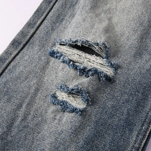 Detail shot of distressed blue denim with heavy stone wash and white fiber fraying