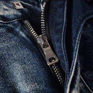 Macro detail of high-quality silver metal zipper and button on washed denim jeans