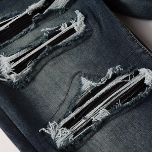 Distressed dark blue men's jeans with patchwork ripped details and slim high street style