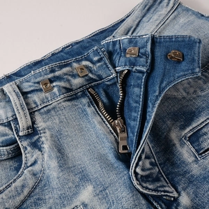 Détail d'un jean vintage bleu clair doté d'une fermeture unique à trois crochets métalliques