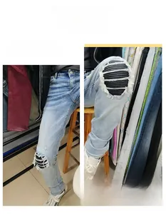 Detailed view of ripped light blue slim denim jeans with pleated biker knee patches