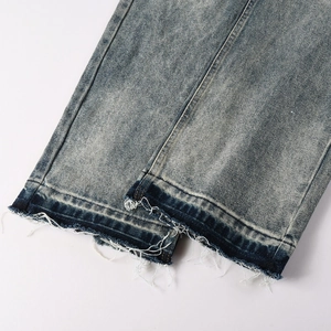 Detail of vintage blue denim jeans with distressed raw hem and stone washed texture