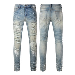 Detail of light blue slim fit jeans featuring hand-distressed holes and paint splatter effects