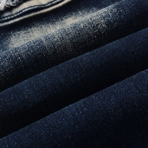 Macro view of distressed dark blue denim fabric showing vintage wash and twill texture