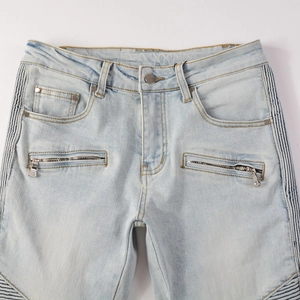 Detail view of light blue biker jeans with horizontal zipper pockets and quilted panels