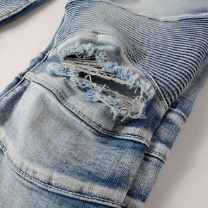 Détails d'un jean moto avec plis en accordéon et déchirures délavées de style rétro vintage
