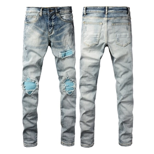 Detail view of light blue ripped jeans with blue striped fabric patches and washed texture