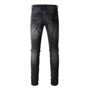 Détail du jean slim noir délavé présentant le design des poches arrière et l'effet usé