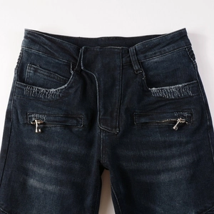 Detailed macro view of deep blue denim jeans with decorative zippers and distressed pockets