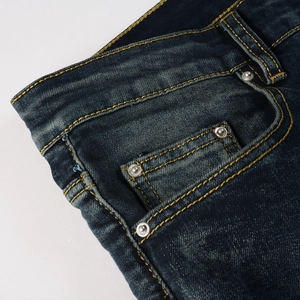 Detail of blue denim jeans featuring waist pockets, metal rivets, and yellow stitching