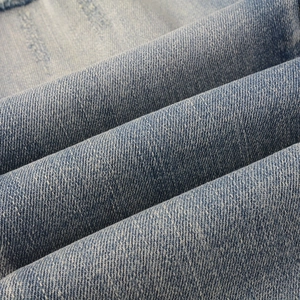 Gros plan sur le tissu denim bleu avec texture sergée et effets délavés