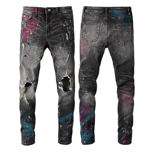 Detailed view of heavy distressed knees and multicolor paint splatter on slim fit jeans