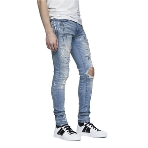 Detail of slim-fit light blue jeans featuring vintage distressed holes and white paint splatters