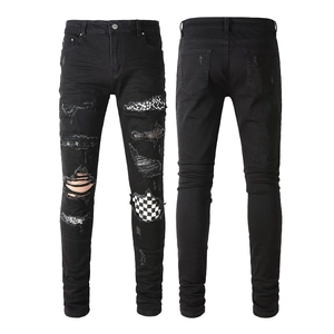Detail view of slim fit black jeans with distressed patches and checkerboard pattern