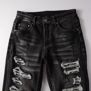 Détail de jean slim gris anthracite usé avec des patchs imprimés uniques dans les trous
