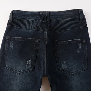 Detail of biker jeans with pleated waistband and distressed back pockets on denim