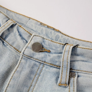 Detail of light blue washed denim waist with silver metal button and yellow contrast stitching